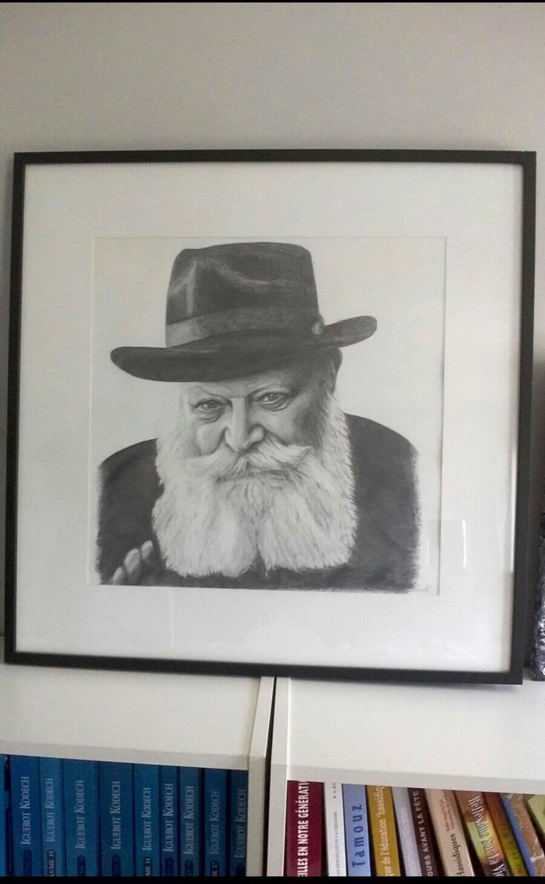 Le portrait du Rabbi encadré sous passe-partout blanc, posé sur une bibliothèque